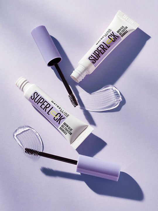 Zwei Maybelline Superlock Augenbrauengele mit geöffneter Verpackung und Textur-Abdrücken.