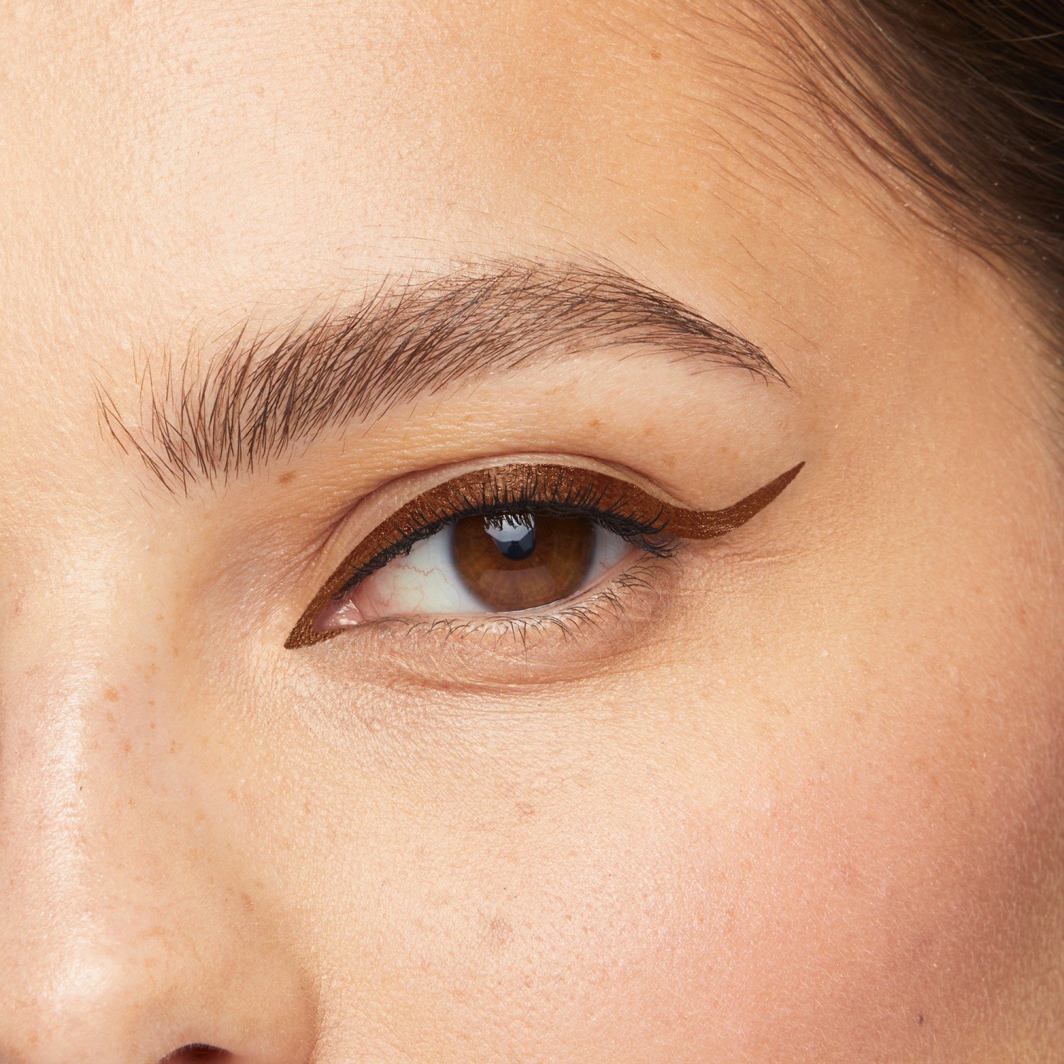 Braunes Auge mit braunem Eyeliner und natürlich geformten Augenbrauen