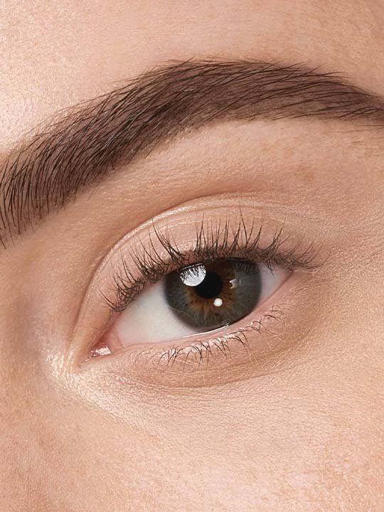 Makroaufnahme eines ungeschminkten Auges mit definierter Augenbraue und natürlichem Wimpernlook.