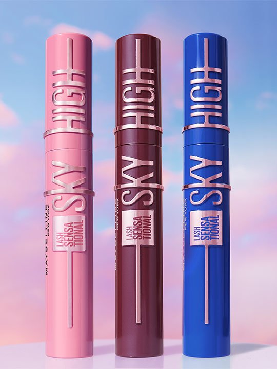 Drei stehende Maybelline Lash Sensational Sky High Mascaras in Pink, Burgunder und Blau vor einem pastelligen Himmel.