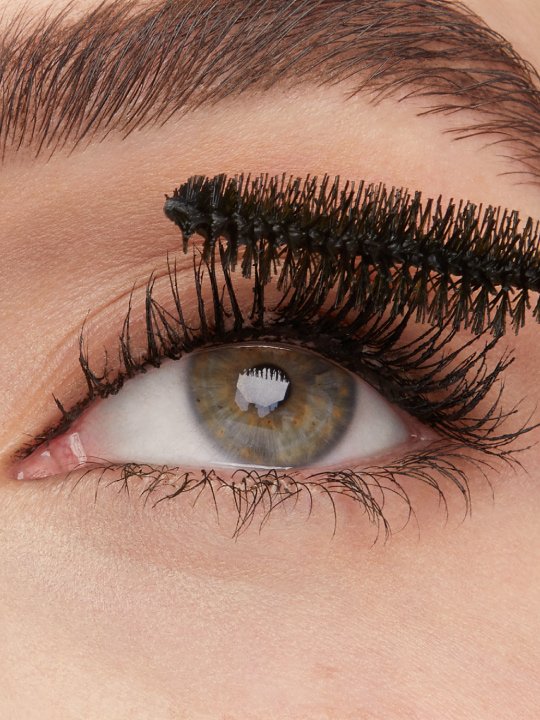 Nahaufnahme eines Auges, das mit Mascara für lange Wimper getuscht wird.