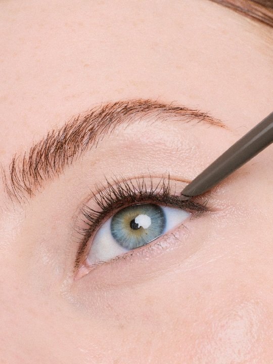 Nahaufnahme eines Auges bei dem mit dem braunen Lasting Drama Automatic Liner entlang des oberen Wimpernkranzes ein Eyeliner gezogen wird