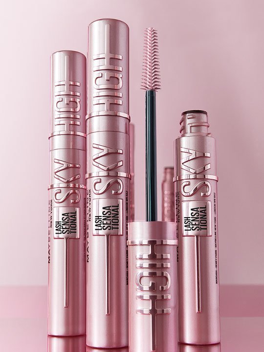 Mehrere roséfarbene Maybelline Lash Sensational Sky High Mascara-Tuben, eine davon geöffnet mit sichtbarer Bürste.