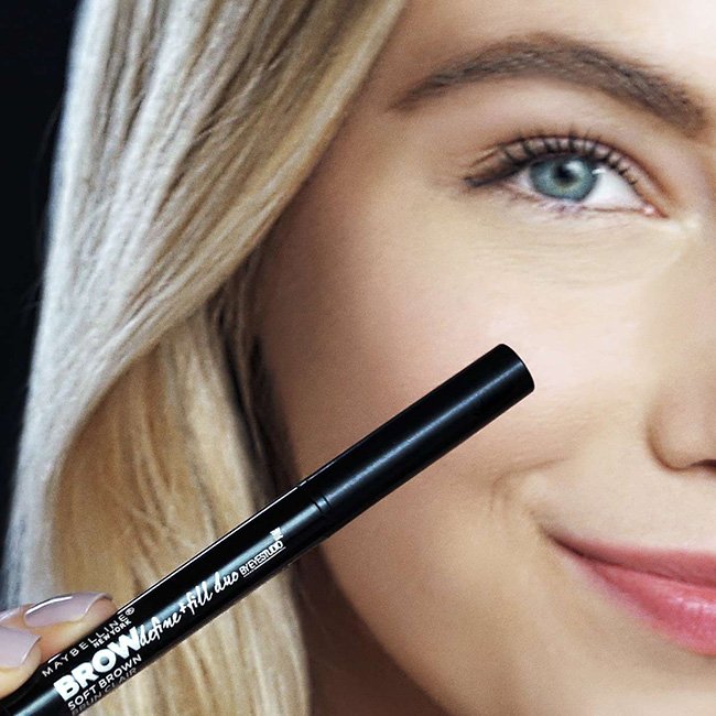 Ein Modell hält das Maybelline Brow Define And Fill Duo Produkt in der Hand
