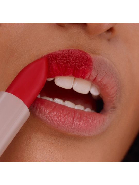Nahaufnahme einer jungen Frau, die sich ihre Lippen mit einem roten Lippenstift schminkt