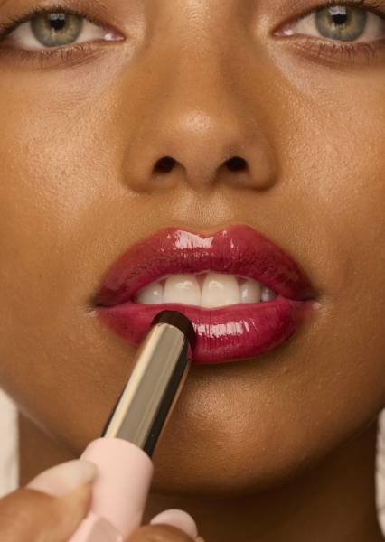 Gesicht einer Frau, die den Maybelline Lifter Glaze Oil Balm auf ihre Lippen aufträgt