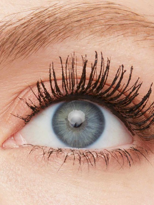 Nahaufnahme eines blauen Auges mit leichten Schlupflidern und getuschten Wimpern
