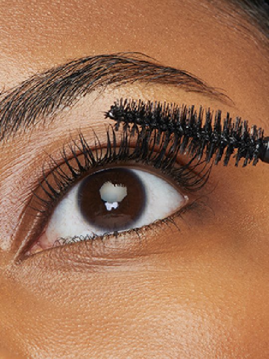Nahaufnahme eines natürlich geschminkten braunen Auges, dass mit Mascara getuscht wird