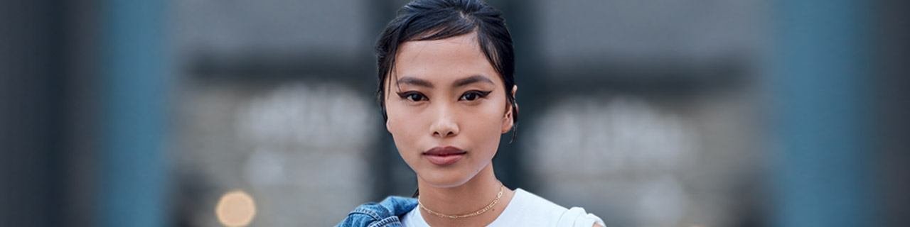 Make-up Trends illustratives Bannerbild – Porträt einer Frau, die Statement-Eyeliner trägt, mit einer Jeansjacke über der Schulter