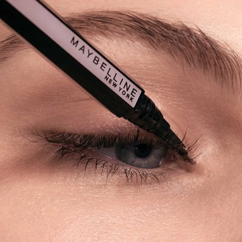 Frau zieht mit einem Maybelline Eyeliner einen Lidstrich am oberen Wimpernkranz