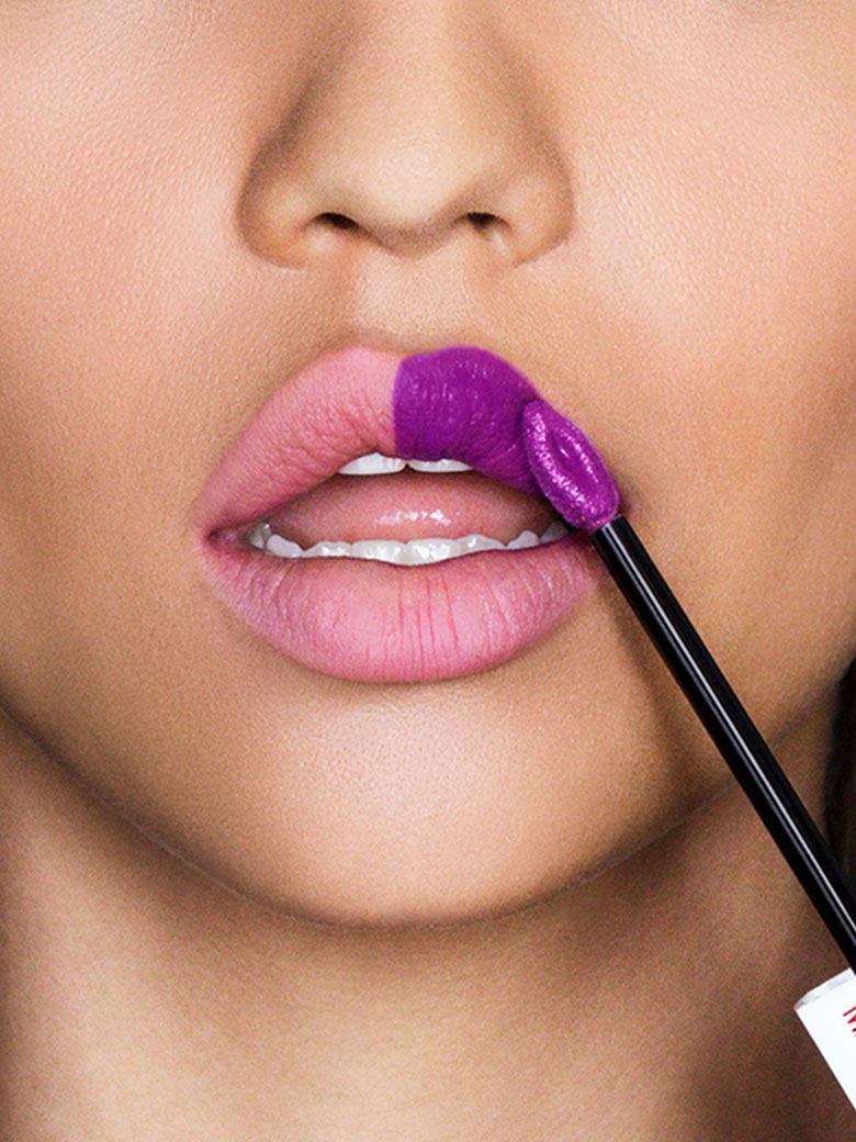 Frau die mit einem flüssigen Lippenstift ihren Amorbogen nachzeichnet