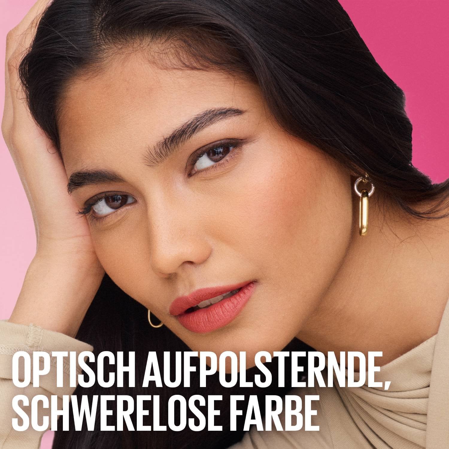 Nahaufnahme einer jungen Frau mit dunklem Haar, die in die Kamera blickt, ihre Hand stützt ihren Kopf, sie trägt korallenfarbenen Lippenstift.