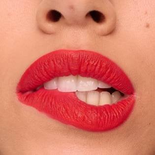 Nahaufnahme einer Frau, die sich auf ihre rot geschminkten Lippen beißt