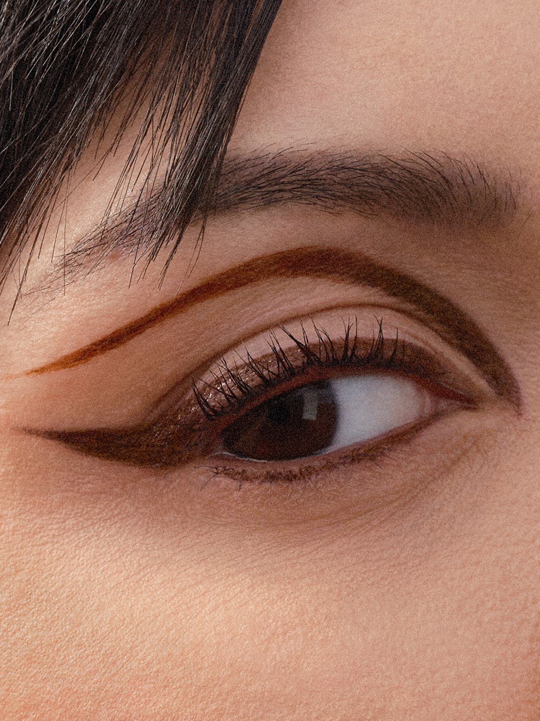 Auge einer Frau, die einen braunen Eyeliner am oberen Wimpernkranz sowie oberhalb der Lidfalte trägt